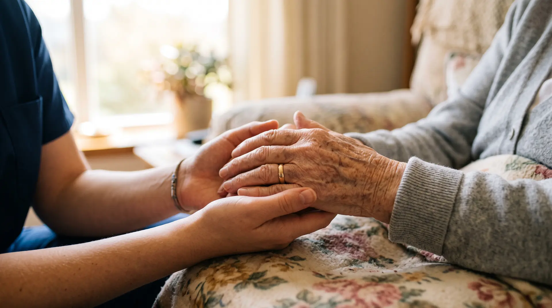 A caregiver gently holding an elderly client's hands